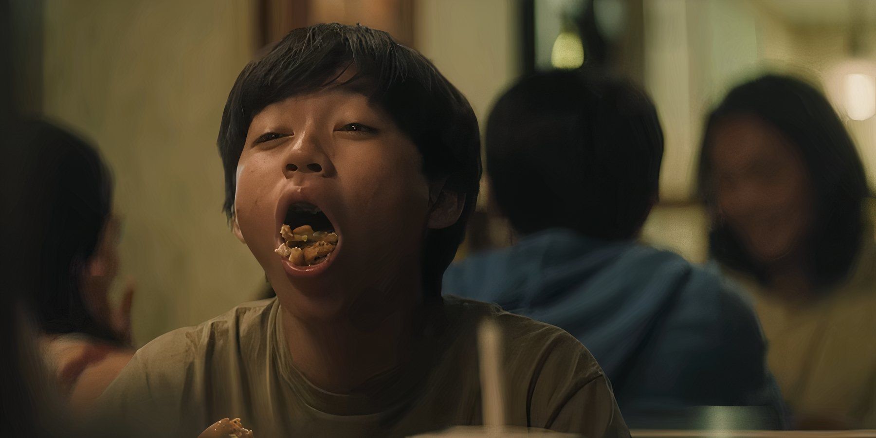Actor Izaac Wang as Chris Wang in the movie "Didi" showing the food in his mouth to camera.