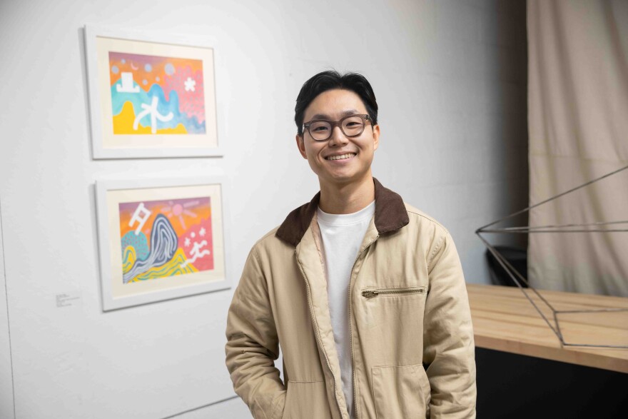Jae Hyun Choi poses in front of his piece “Immanence,” 2024, Acrylic, pastel chalk on canvas sheet, diptych, during the Dallas Asian American Art Collective’s first annual show at the Cedars Union Dallas on Saturday, Nov. 23, 2024. Pei-en Yang’s “Three Homes,” 2024, transparency film, photography, collage, can be seen on the left.