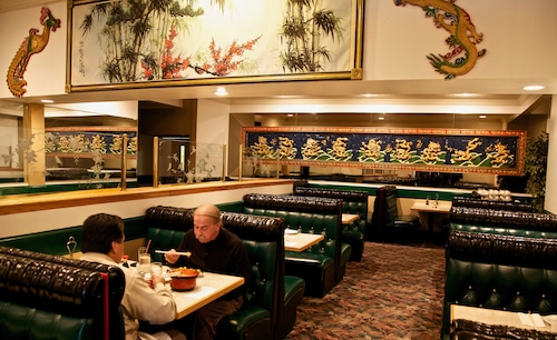 two men sit at a restaurant booth eating in a chinese restaurant