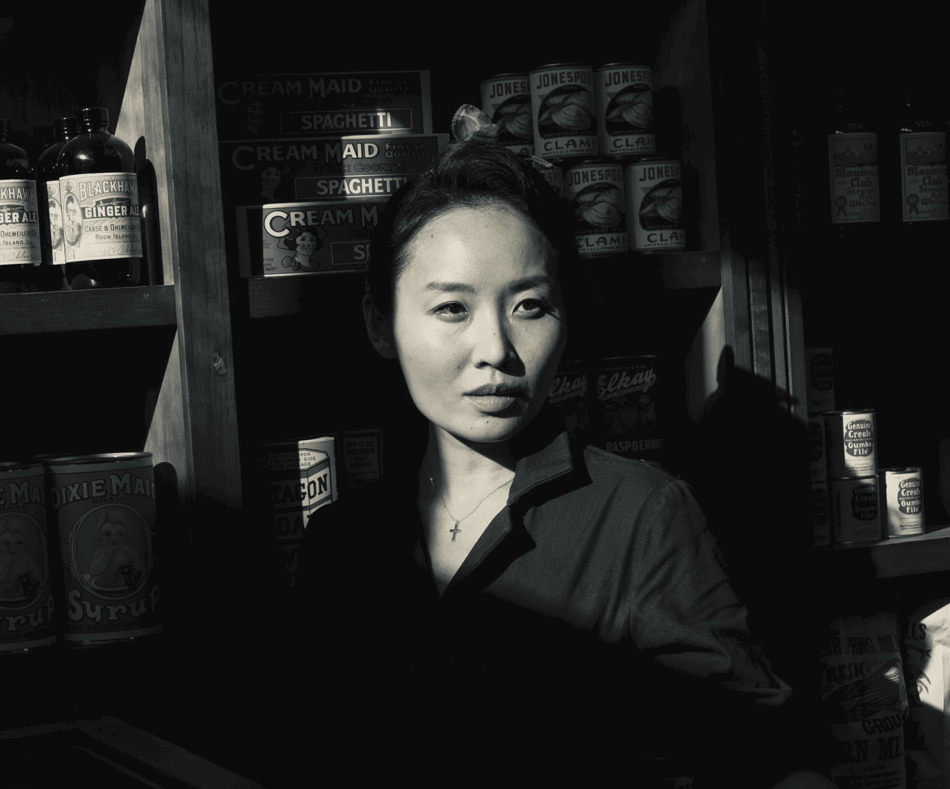 black-and-white image of Asian woman against shelf of goods