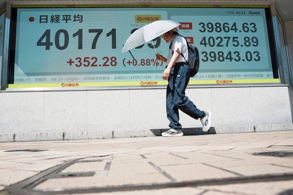 A person walks in front of an electronic stock board showing Japan's Nikkei index at a securities firm Tuesday, July 22, 2025, in Tokyo. (AP Photo/Eugene Hoshiko)