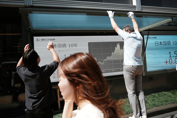 Maintenance workers repair an electronic board of financial indexes, at a securities firm Tuesday, July 22, 2025, in Tokyo. (AP Photo/Eugene Hoshiko)