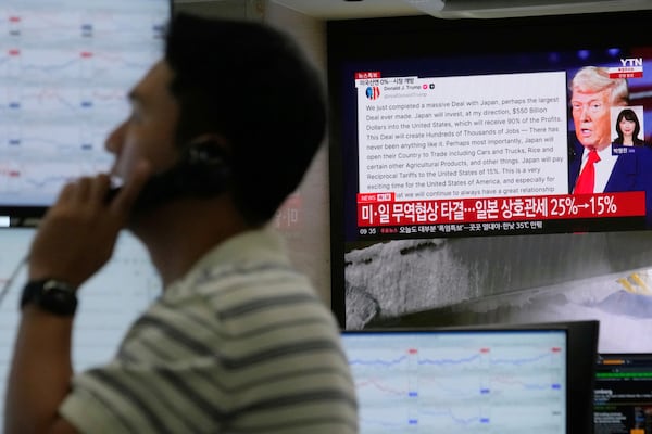 A currency trader works near the screen showing news reporting with a picture of President Donald Trump at the foreign exchange dealing room of the Hana Bank headquarters in Seoul, South Korea, Wednesday, July 23, 2025. (AP Photo/Ahn Young-joon)