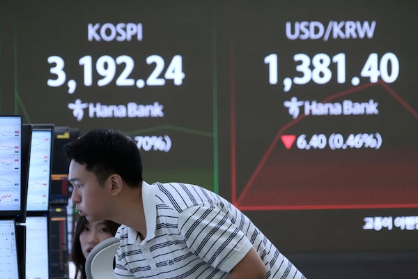A currency trader watches monitors near a screen showing the Korea Composite Stock Price Index (KOSPI), top left, and the foreign exchange rate between U.S. dollar and South Korean won at the foreign exchange dealing room of the Hana Bank headquarters in Seoul, South Korea, Wednesday, July 23, 2025. (AP Photo/Ahn Young-joon)