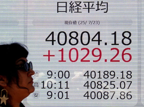 A person walks in front of an electronic stock board showing Japan's Nikkei index at a securities firm Wednesday, July 23, 2025, in Tokyo. (Kyodo News via AP)