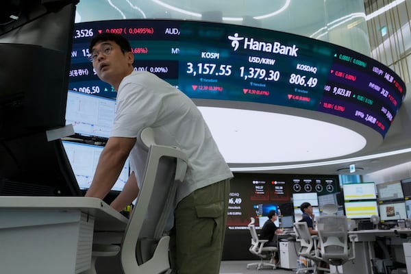 A currency trader watches monitors near a screen showing the Korea Composite Stock Price Index (KOSPI), top center left, and the foreign exchange rate between U.S. dollar and South Korean won, top center, at the foreign exchange dealing room of the Hana Bank headquarters in Seoul, South Korea, Wednesday, July 23, 2025. (AP Photo/Ahn Young-joon)