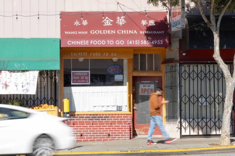 A storefront with Wang Wah Golden China Restaurant on the canopy, with people and cars passing by