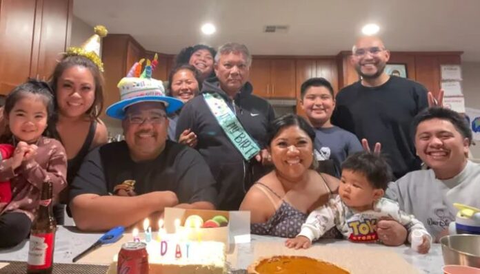 Rolando Yanga is center wearing a birthday sash and is surrounded by family and friends